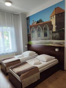 two beds in a room with a painting on the wall at Hotelik w Centrum in Toruń +39 photos