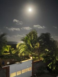 a view of the moon over palm trees at night at Villa frente al Mar cerca a Barranquilla in Tubará