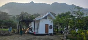 Una pequeña casa blanca con una escalera que conduce a ella. en ปิงโค้งเม้าท์เท่นวิว, en Ban Yang
