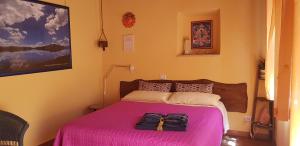 a bedroom with a pink bed with two bags on it at B&B Campo del Mare in Sirolo