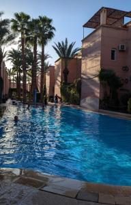 マラケシュにあるRiad Noureddineのヤシの木と建物のある大きな青いプール