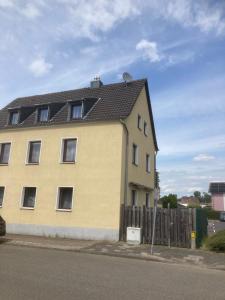 a yellow house with a black roof and a fence at Monteurwohnung in Rommerskirchen in Rommerskirchen