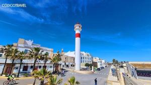 a lighthouse in the middle of a street with palm trees at Apartamento patio Andaluz in Rota +4 photos