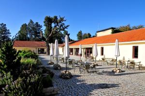 eine Terrasse mit Tischen, Stühlen und Sonnenschirmen vor einem Gebäude in der Unterkunft Pousada Convento de Belmonte in Belmonte