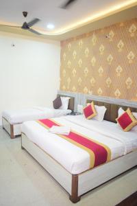 two beds in a hotel room with white sheets at Vinayak shree hotel in Indore +1 photo