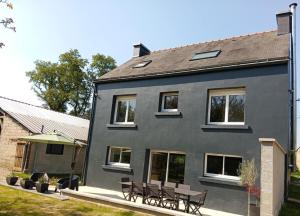 a gray house with benches in front of it at Gîte - La Maison in Kernascléden