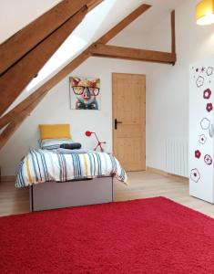 a bedroom with a bed and a red rug at Gîte - La Maison in Kernascléden