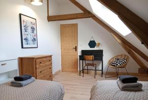 a attic bedroom with two beds and a desk at Gîte - La Maison in Kernascléden