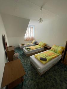 a room with three beds and a table at Tabán Vendégház in Balatonlelle