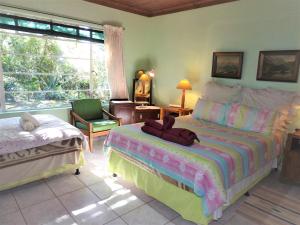 ein Schlafzimmer mit zwei Betten und einem Stuhl in der Unterkunft Dinizulu Cottage in Hluhluwe