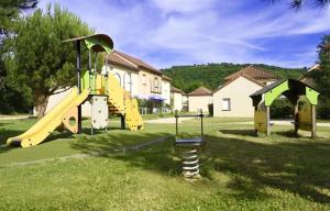 a playground with a yellow slide in a yard at La belle histoire in Montignac