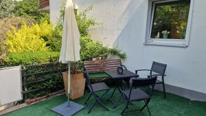 a table and chairs and an umbrella on a patio at Gemütliche Ferienwohnung nähe Schloss Benrath & Rhein Düsseldorf Urdenbach in Düsseldorf