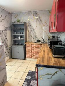 a kitchen with red cabinets and a marble wall at BB-Spacious 1 Double room in Wembley in London