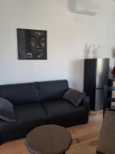 a living room with a black couch and a painting at cottage LES SENS CIEL in Saint-Martin