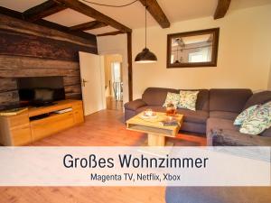 a living room with a couch and a tv at Ferienwohnung im Sauerland Hunde willkommen Kamin und Garten am Waldrand Muehls-Sauerland in Lennestadt