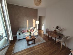 a living room with a couch and a table at Charmant T2 avec cachet - Au cœur de Poissy & à 20 min de Paris ! in Poissy