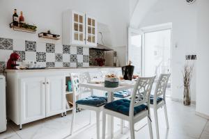 a white kitchen with a white table and chairs at Biancomora in Crispiano
