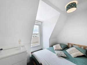 a white bedroom with a bed and a window at Pleasant Studio in Saint-Brieuc