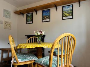 a table with chairs and a vase of flowers on it at Foresters Inn Cottage in Parkend