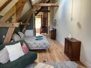 a living room with a green couch and wooden floors at Moulin de Maupoy in Saint-Symphorien-de-Marmagne