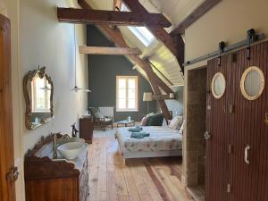 a bedroom with a bed and a bathroom with a sink at Moulin de Maupoy in Saint-Symphorien-de-Marmagne