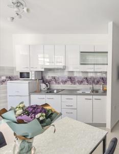 a kitchen with white cabinets and a table with flowers at Apartment Silvia in Makarska