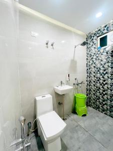 a bathroom with a white toilet and a sink at Radhyam Retreat in Ayodhya