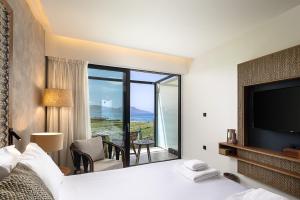 a hotel room with a large bed and a television at Kimpton La Mer Crete by IHG in Georgioupolis