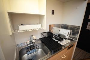 a kitchen with a stainless steel sink and a shelf at goom Monthly Nakasu Maxim in Fukuoka