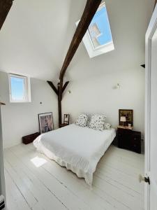 a white bedroom with a bed with pillows on it at Villa Ecureuils accessible à pied de la gare de Gien à 1h30 de Paris in Gien