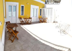 a patio with chairs and tables and a yellow wall at La Parata in Ponza