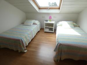 a attic bedroom with two beds and a window at Chalet Playa Portonovo in Sanxenxo