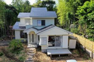 una pequeña casa blanca con un banco delante en 温泉付き 自然に囲まれながら別荘生活を満喫 1棟貸切 湖畔 バーベキュー 長期滞在 ファミーユ伊豆の瞳, en Ito