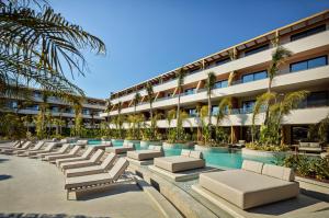 a hotel with a row of chaise lounge chairs next to a pool at XO CAPE ARNNA Fethiye in Fethiye