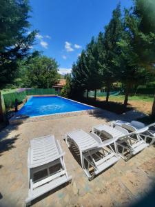 a group of white lounge chairs next to a swimming pool at Villa Dalmatina with pool in Kumanovo