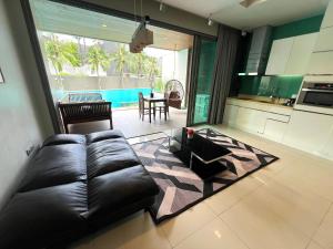 北芭堤雅Beachfront Luxe with Pool Access and Terrace的带皮沙发的客厅和厨房