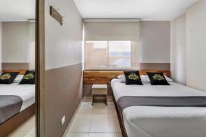 two beds in a small room with a window at Hotel de la Salle in Bogotá