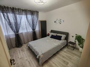 a bedroom with a bed and a window with curtains at NGR Residence in Ploieşti