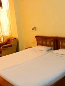 a bedroom with a bed and a chair and a window at Hotel PB Thana in Shillong