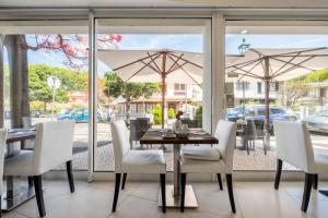 a dining room with a table and chairs and an umbrella at White Waters Hotel in Machico