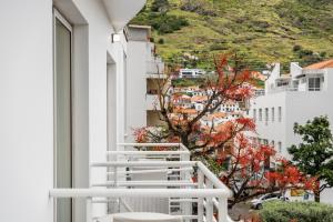 a white balcony with a view of a city at White Waters Hotel in Machico