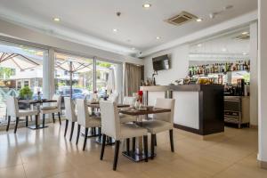 a dining room with tables and chairs and a bar at White Waters Hotel in Machico