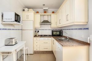 Una cocina con gabinetes blancos, un fregadero y un microondas. en Novo Atlántico Golf, Novo Sanctipetri, en Novo Sancti Petri
