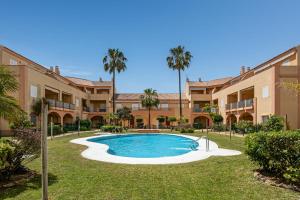 Un patio con piscina y palmeras. en Novo Atlántico Golf, Novo Sanctipetri, en Novo Sancti Petri