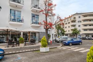 a parking lot with cars parked in front of a building at White Waters Hotel in Machico