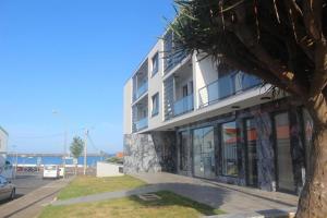 a white building with a tree in front of it at Praia Horizonte Studio's - RRAL nº3195 in Praia da Vitória