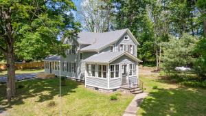 a small white house in a yard with trees at Farmhouse Retreat, Outdoor Dining, Fire-Pit, Fast Wifi, Golf and 3-Acre Privacy in Valatie