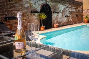 a bottle of wine and two glasses next to a swimming pool at Villa Hobland Barn in Fritton