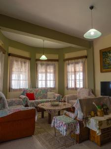 a living room with couches and tables and windows at Katina's Farm House in Áno Lekhónia +14 photos