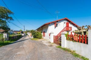 a street with a white house and a red fence at Joli T3 Pays Basque Tarnos Landes in Tarnos
